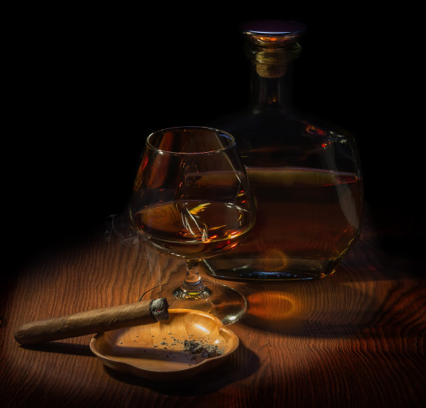 一瓶威士忌，一杯满杯的威士忌，还有一支烟在烟灰缸里抽着图片下载
