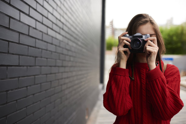 年轻的女性旅行者制作业余照片的城市，而漫步在户外与复古相机，时髦的女孩花时间在爱好制作图片站在复制空间的广告图片下载