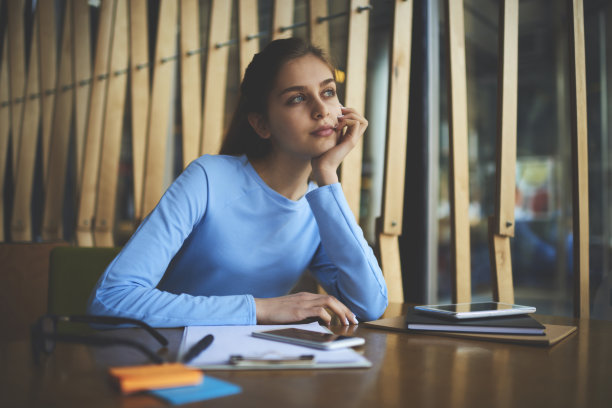 有思想的女学生，美丽的蓝眼睛望着别处，一边做梦和思考。沉思的青少年喜欢在大学课间休息时坐在书桌前阅读文学书籍消遣时间图片下载