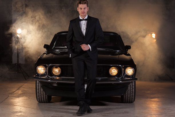 年轻英俊的男子在汽车修理厂与经典车图片下载