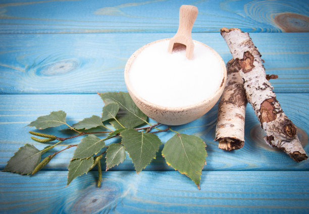 木糖醇-糖的替代品。白桦糖在蓝色木制背景。素材图片