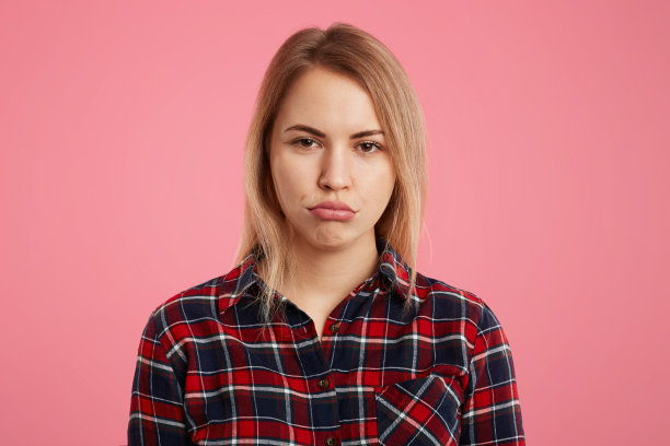迷人的虐女模特曲线嘴唇被亲密的人冒犯，表达了她的不满，孤立于粉红色的背景。愁眉苦脸的漂亮女人图片下载