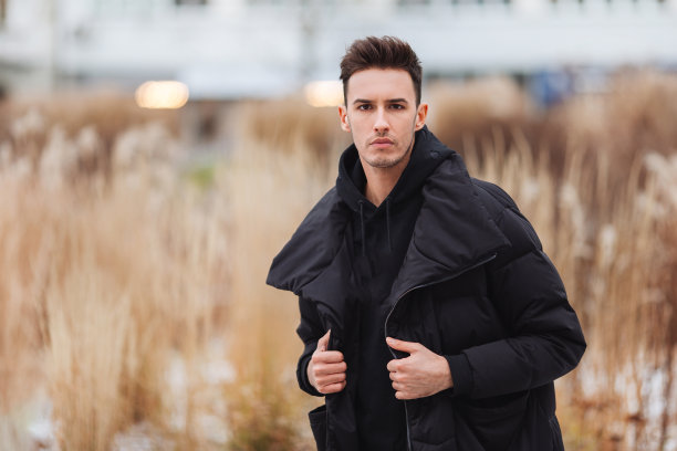 时尚的男人走在街上。冬天冷。大夹克配白色运动鞋。长途跋涉背景街。Profecional模型照片。图片下载