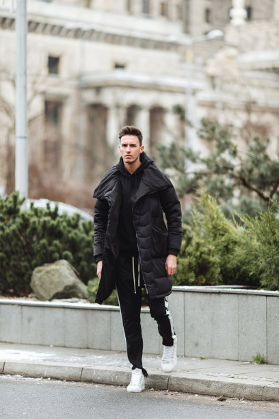 时尚的男人走在街上。冬天冷。大夹克配白色运动鞋。长途跋涉背景街。Profecional模型照片。图片下载