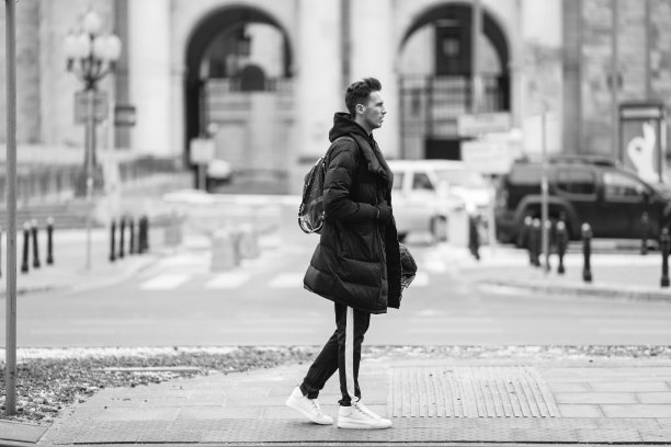 时尚的男人走在街上。冬天冷。大夹克配白色运动鞋。长途跋涉背景街。Profecional模型照片。图片下载