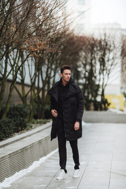 时尚的男人走在街上。冬天冷。大夹克配白色运动鞋。长途跋涉背景街。Profecional模型照片。图片下载