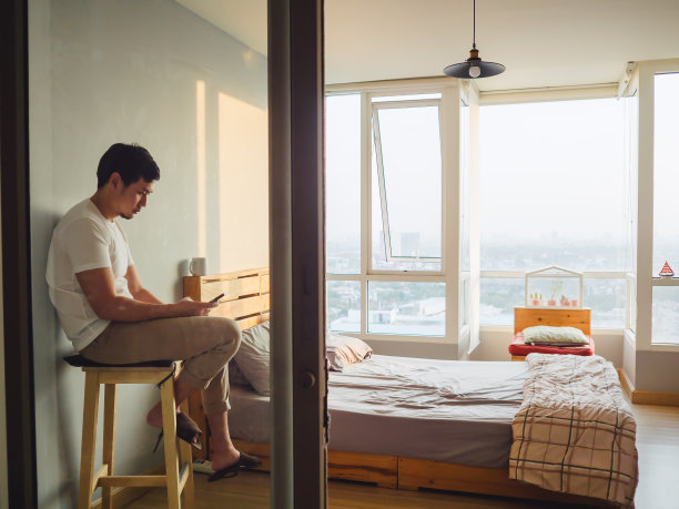 孤独的男人在房间里聊手机，喝咖啡，看日落。图片下载