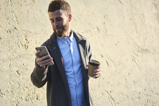 年轻帅气，穿着考究的男性热门旅游博主分享旅行的照片和视频，同时使用智能手机上的导航应用程序连接到快速4G网络漫游图片下载