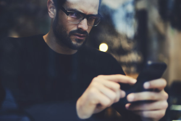 英俊潇洒的男留学生在社交网络上与朋友聊天，分享照片和视频文件，通过连接5G无线的智能手机讨论派对策划的想法图片下载