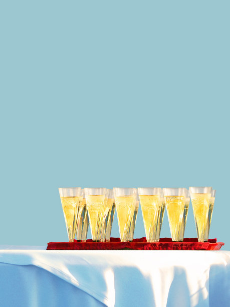户外派对，婚礼。服务。自助餐。配有香槟的笛子、酒杯放在桌上的托盘上，桌上铺着白色桌布，以浅蓝色为背景图片下载