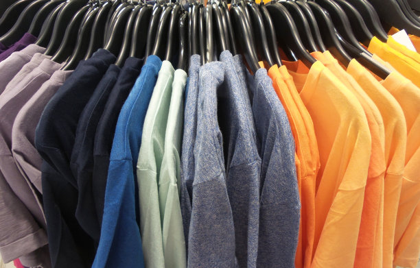 彩虹色的衣服挂在零售店的衣架上。时尚与购物概念图片下载