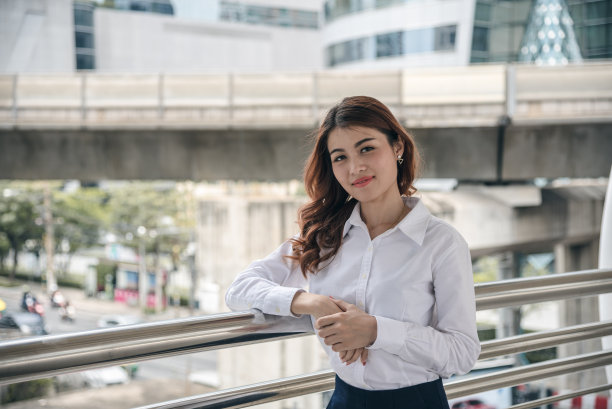 美丽的亚洲女人的肖像看起来快乐和自信是站在户外的同时感觉与工作的成功。图片下载