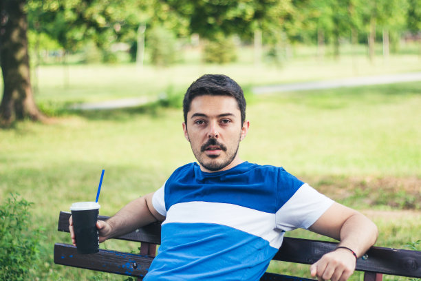 年轻人在公园里喝着最喜欢的咖啡放松。图片下载