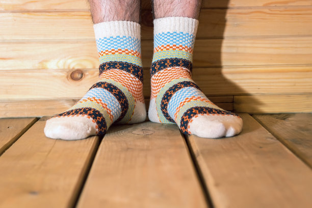 穿有装饰的袜子的男人。男人的脚踩在木地板上。图片下载