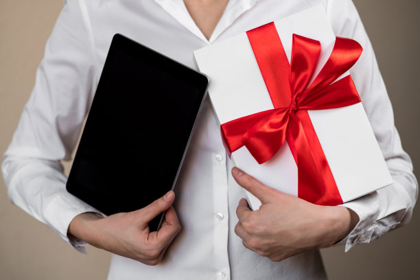 一位女士腋下夹着一块银质牌匾和一个礼品盒图片下载