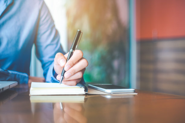 女人的手在记事本上用钢笔写字。素材图片