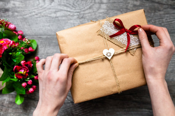 女人手里拿着包装好的礼物，情人节，浪漫的照片。浪漫的灰色木质背景，配爱心礼品，适合做广告图片下载