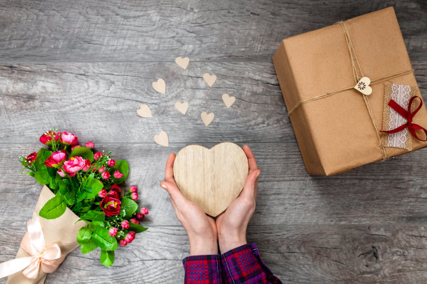 女人手里拿着一颗木制的心，情人节，浪漫的照片。带礼物和一束鲜花，带爱心和礼物，适合做广告图片下载