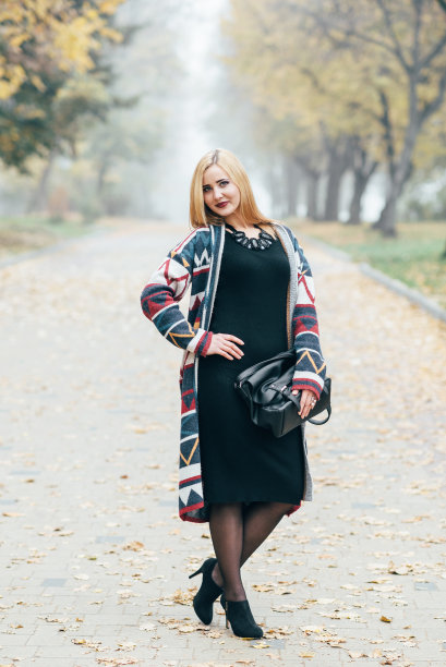 迷人的年轻金发女人在秋天的公园里穿着黑色的裙子图片下载