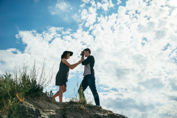一对年轻夫妇在山上，一个男人正在给他的女朋友拍照图片下载