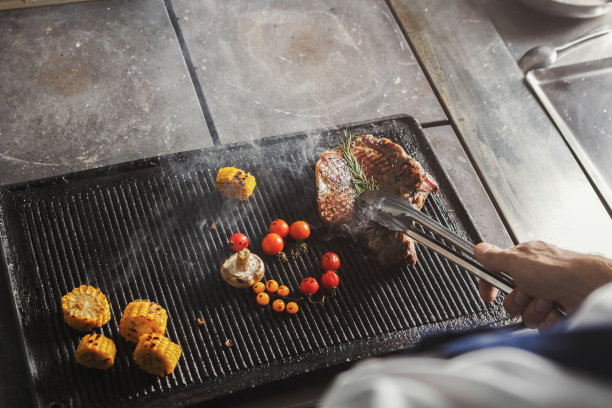 厨师在餐厅厨房烹饪多汁的牛排图片下载