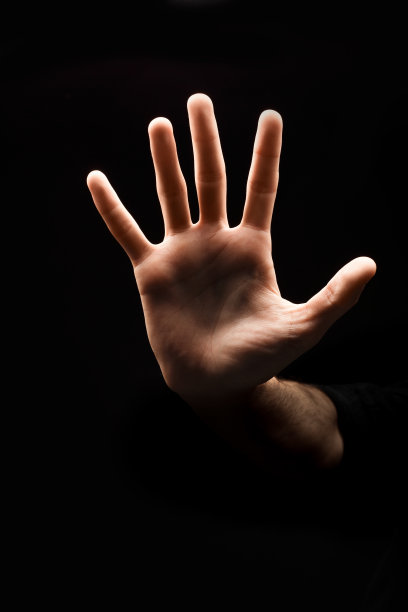 一名男子用手在黑色背景下做停车标志素材图片