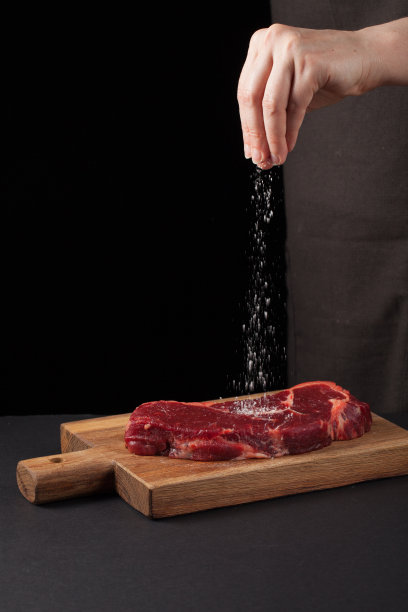 牛排和盐的厨师在背景与自由空间的文字设计或标识菜单餐厅。垂直的照片。食品的背景。黑色文本区域。本空间图片下载