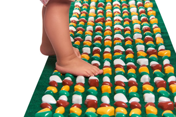 小婴儿的脚上铺着矫形地毯。孤立在白色背景上。图片下载