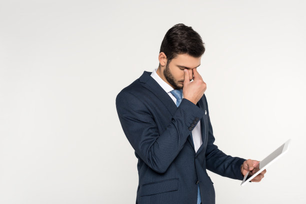 疲惫的年轻商人手持数码平板电脑孤立在灰色素材图片