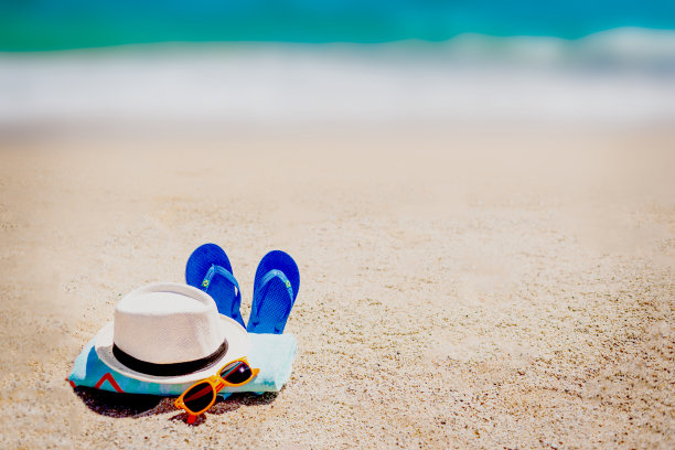 沙滩上有毛巾，人字拖和夏日配饰。度假和旅游项目。热带度假背景图片下载