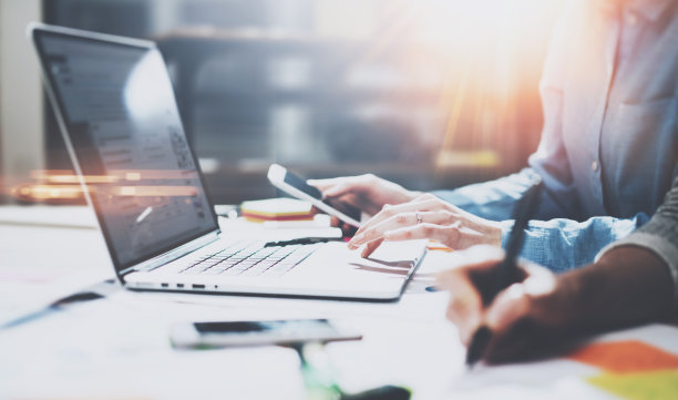 团队合作过程的概念。办公室里有新项目的年轻同事。女孩在用笔记本电脑和智能手机。水平的,模糊的背景。图片下载