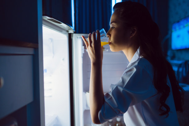 亚洲女性打开冰箱，晚上喝橙汁素材图片