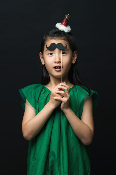可爱的亚洲女人孩子与假胡子和圣诞头装饰在黑色的背景。图片下载