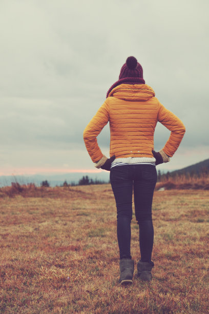 在日落/日出时间走在山上的草地上的女人。图片下载