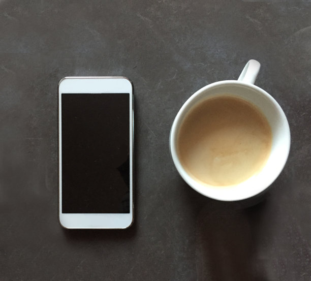 黑色纹理背景上的智能手机和咖啡杯图片下载
