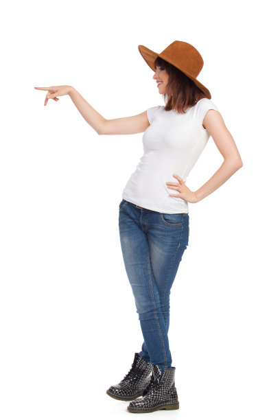 微笑的年轻女子在棕色绒面革帽子是站和指向。侧面孤立图片下载