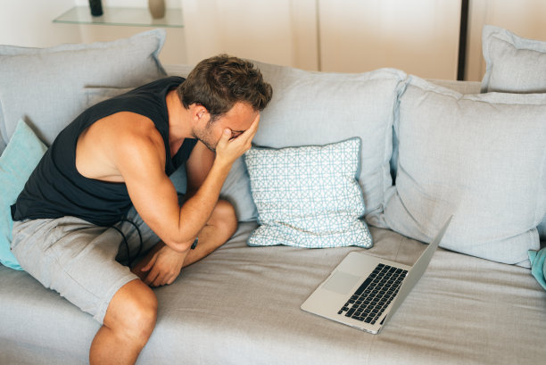 快乐的金发青年男子坐在家里的沙发上看足球图片下载