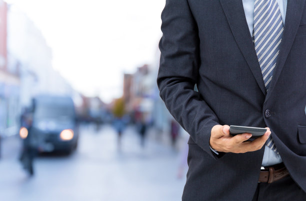 孤立的商人在街上拿着智能手机图片下载