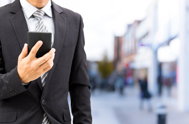 孤立的商人在街上拿着智能手机图片下载