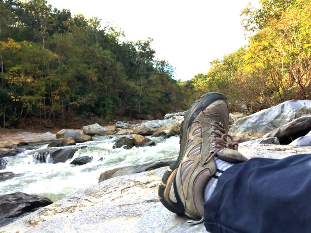 靴子放在小溪附近的岩石上图片下载