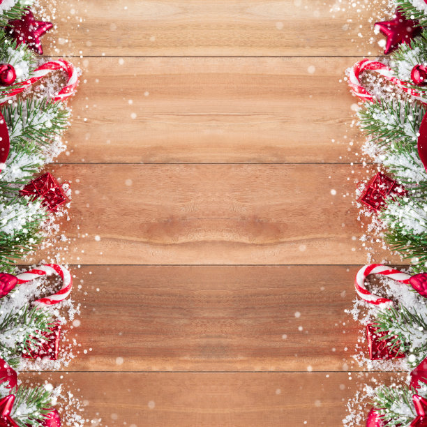 红色的圣诞装饰品与松树和雪装饰在木面板的背景图片下载