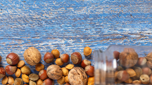 将混合的坚果倒在蓝色的木制桌子上。前视图。本空间图片下载