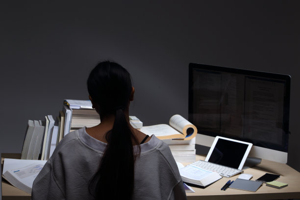 女孩穿着白衬衫读许多课本在桌子上堆放着许多高图片下载