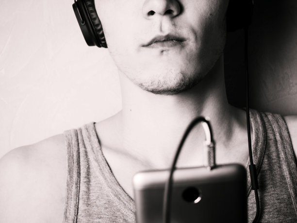 年轻人用耳机听着电话里的音乐。脸是不可见的图片下载