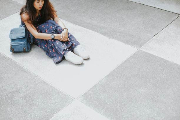 女人拿着包坐在地板上;感到悲伤图片下载