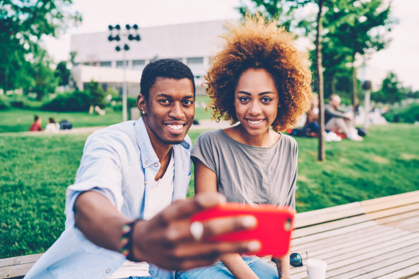 半长肖像微笑的女人卷头发和积极的男人一起自拍在现代电话相机，以分享的图片在社交网络上与朋友使用互联网连接图片下载