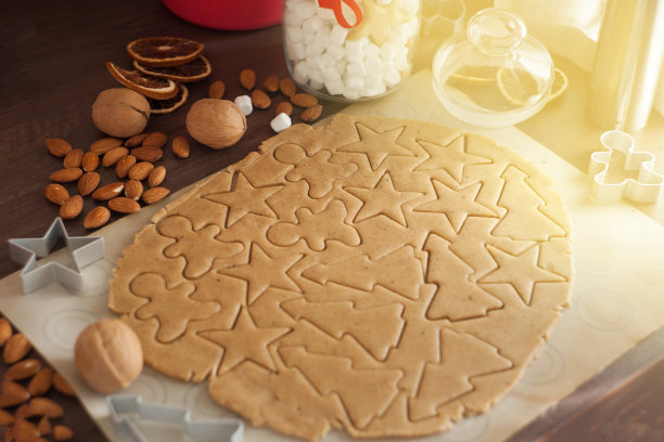 圣诞烘培背景快乐。从以上。生面团放在木板上，用擀面杖和饼干模具做成圣诞节的形状。圣诞饼干的准备图片下载