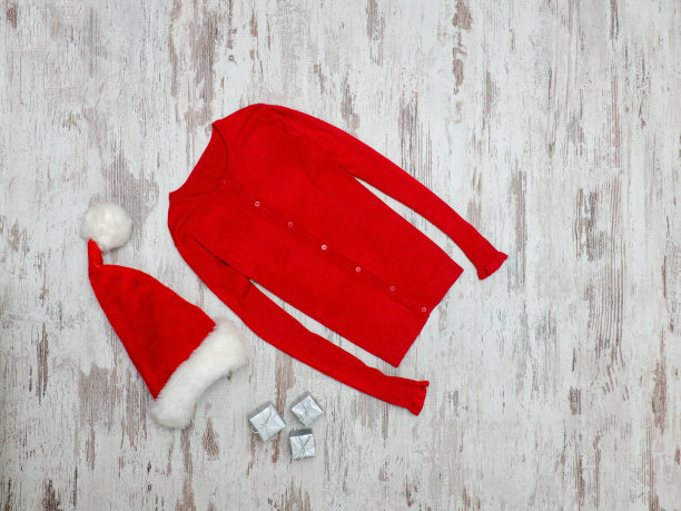 红色的毛衣和圣诞老人的帽子在一个木制的背景。时尚的概念图片下载