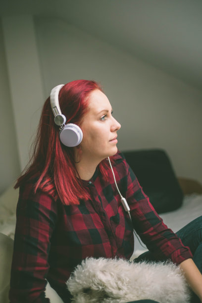 漂亮的年轻女子在家里戴着耳机听音乐图片下载