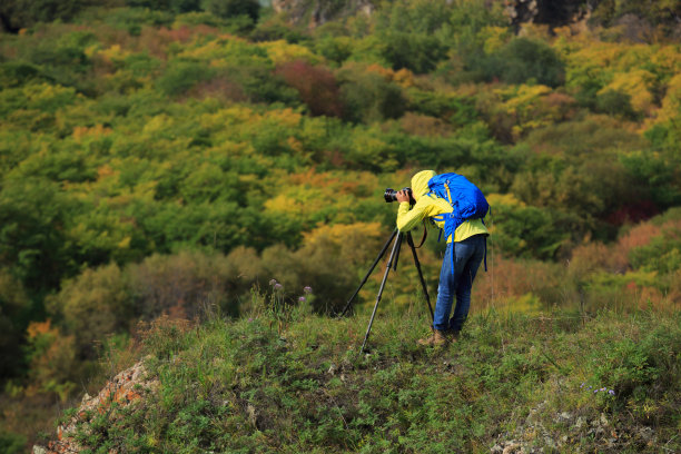 摄影师用专业相机在户外三脚架上拍照图片下载
